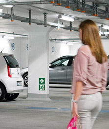 Người phụ nữ ra xe ở một bãi đỗ xe trong nhà ứng dụng công nghệ xanh. - chiếu sáng cửa hàng